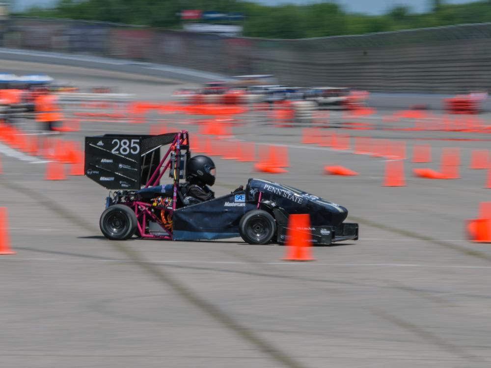 A Formula 1 racecar zooming past orange traffic cones.