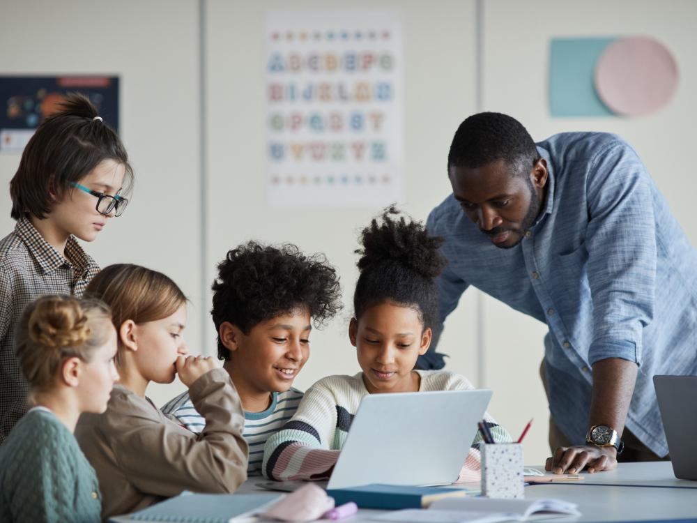Children and a teacher looking at a computer