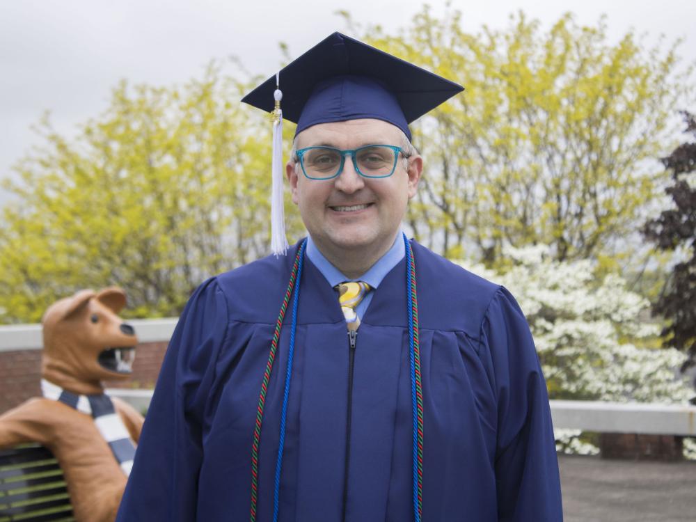 Student wearing commencement regalia and smiling