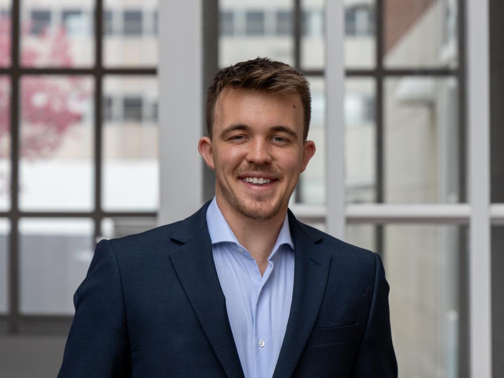 Dan Bransfield poses for a headshot in front of windows at Penn State University Park.
