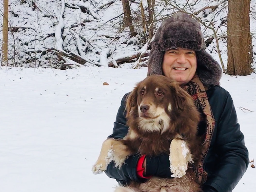 Person holding a dog with snow visible in the background