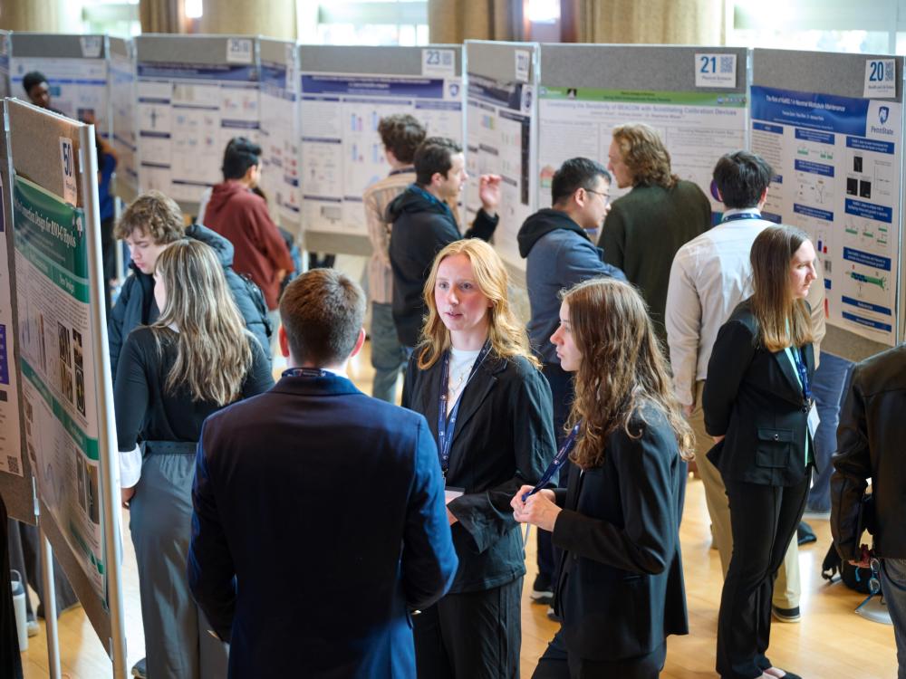Group of students standing with research posters talking