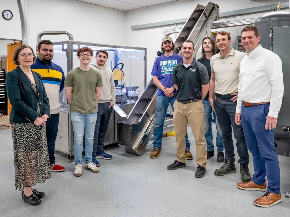 A group of people stand in front of a 9-foot incline conveyor