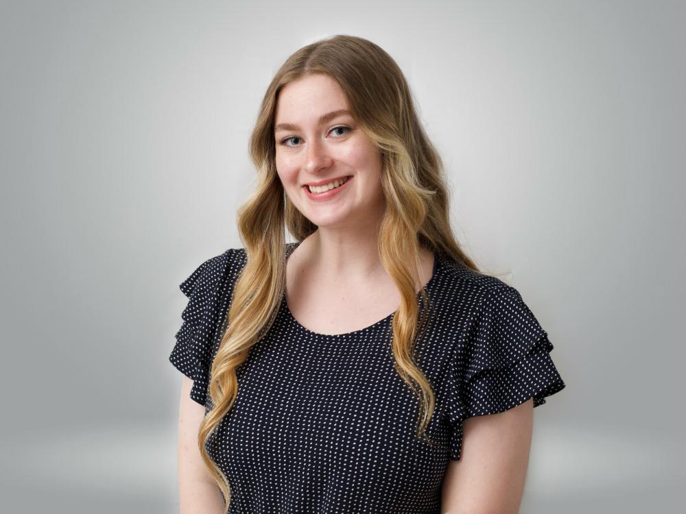 Elizabeth Schachte smiling at the camera against a grey backdrop.