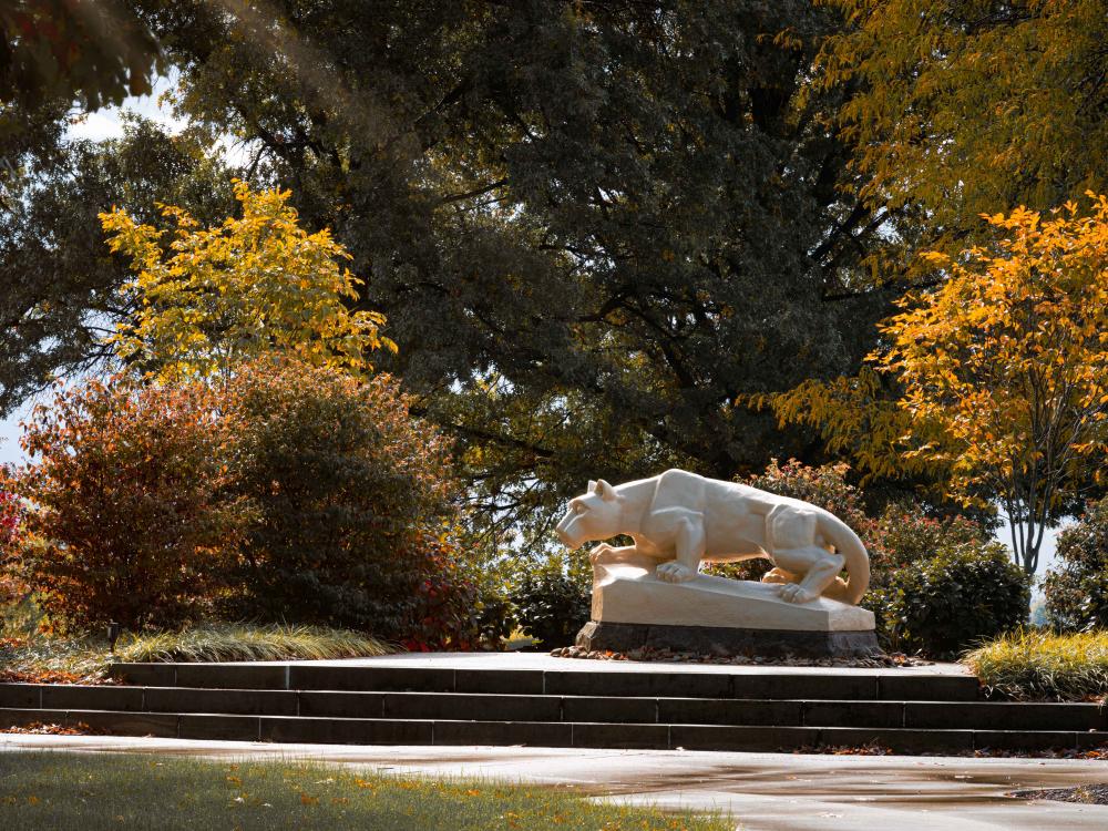The Nittany Lion Shrine at Penn State Fayette stands surrounded by foliage.