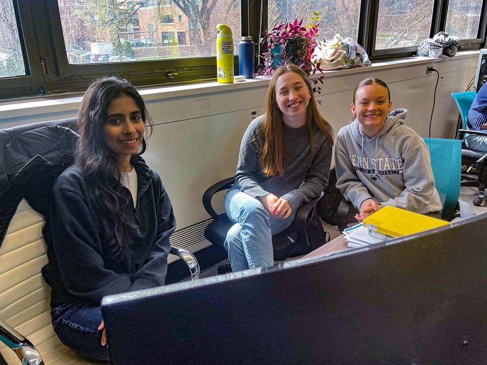 Graduate student Harman and undergraduates Laura and Maria work together at a computer on a research project about waste management.