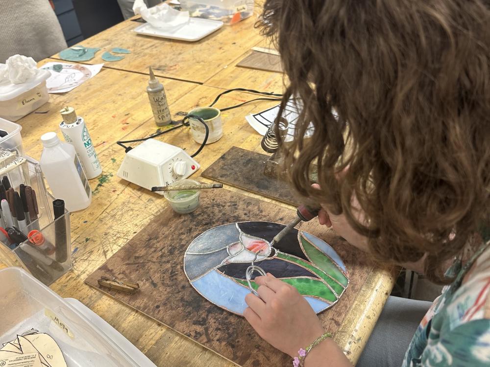 Person working on stained glass in a workshop.