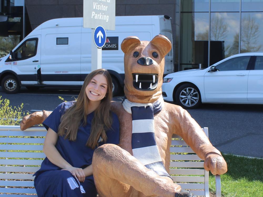 Stephanie Kling, spring 2025 commencement student marshal, sits on a bench with the Nittany Lion
