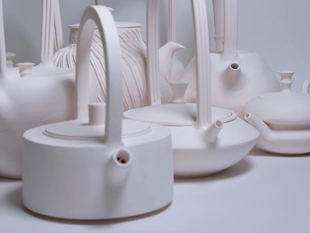 Pieces of ceramic artwork with a white background. Ceramic items look to be tea pots in various sizes and shapes.