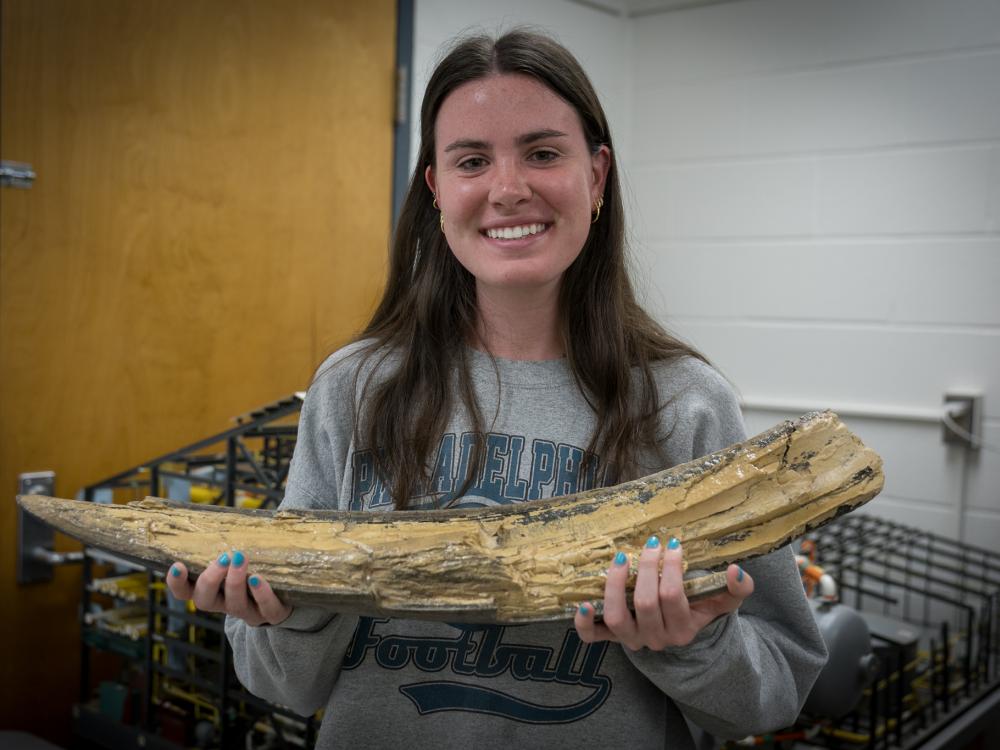 Geosciences student Kaitlin Dasovich holds mastodon tusk