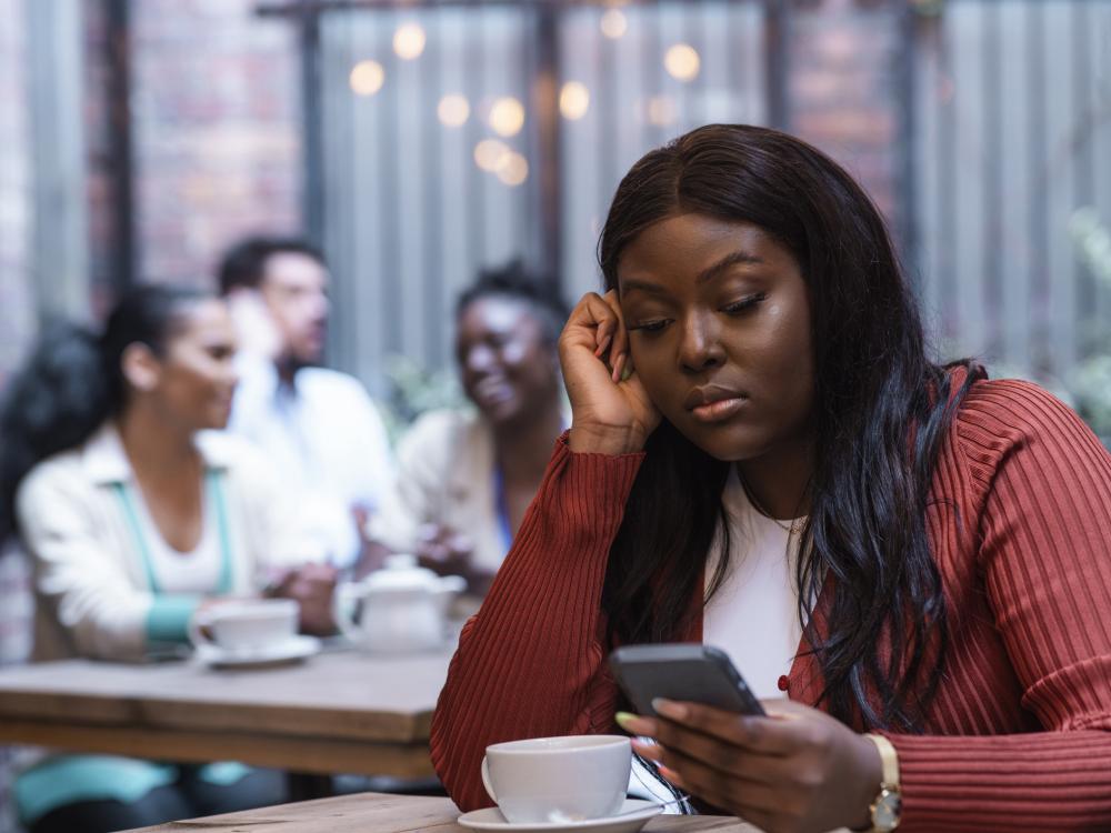 Person in coffee shop on phone looking bored