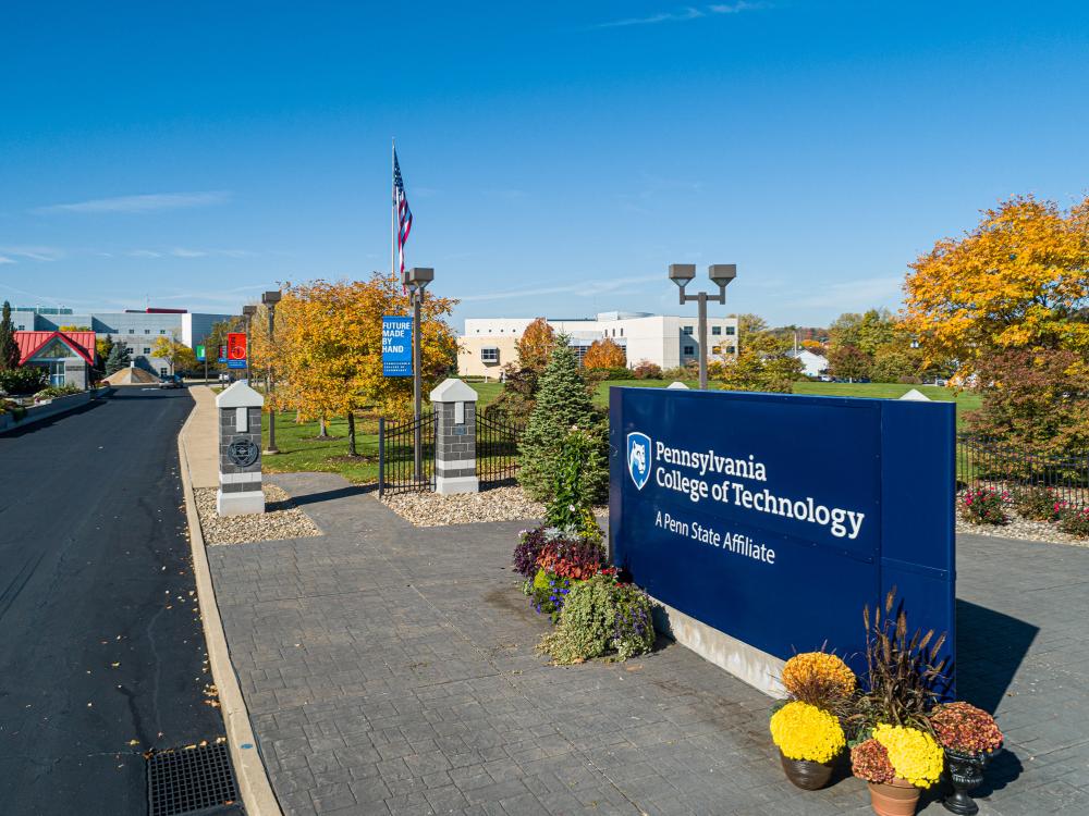 The entrance to the Penn College campus, with an American flag and sign saying the Pennsylvania College of Technology