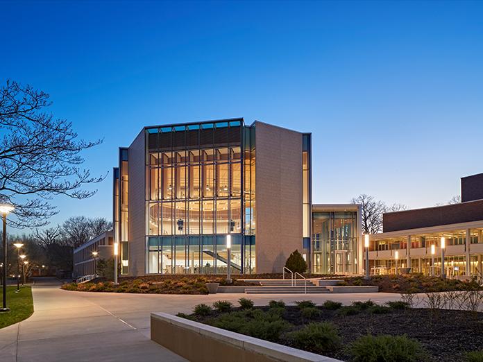 An outside view of a recital hall with grand windows photographed at sunset