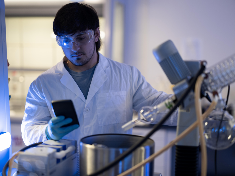 An individual wears a lab coat in a lab environment while interacting with lab materials