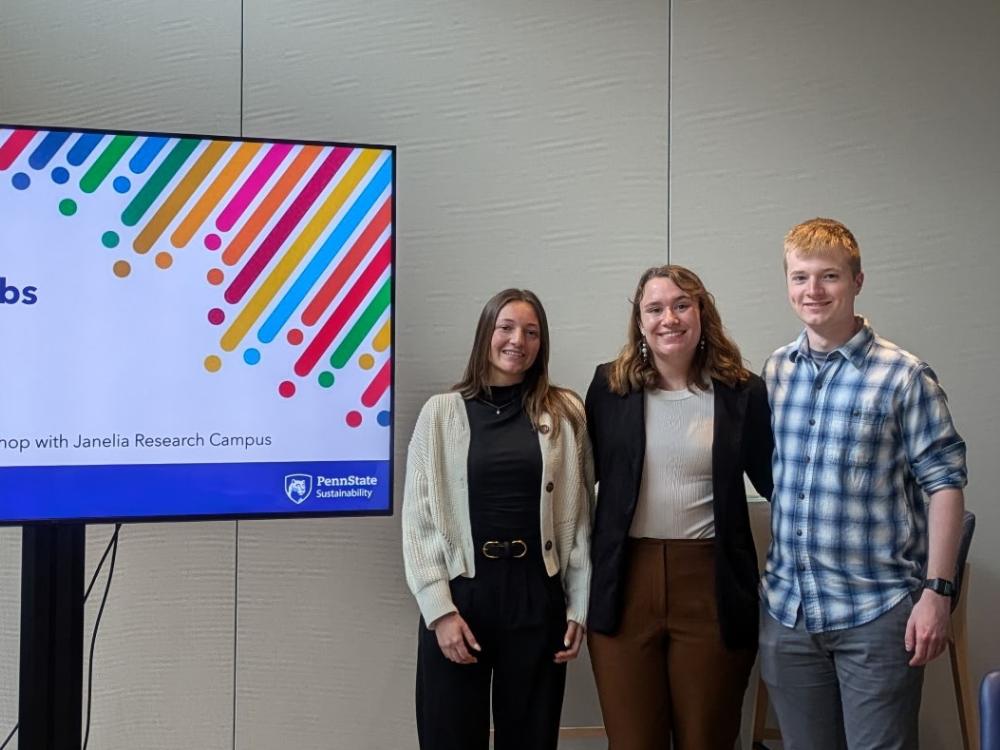 Three students present slides at a research center