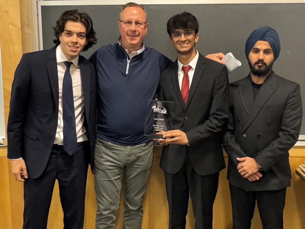 A photo of four people posing for a photo with a trophy.