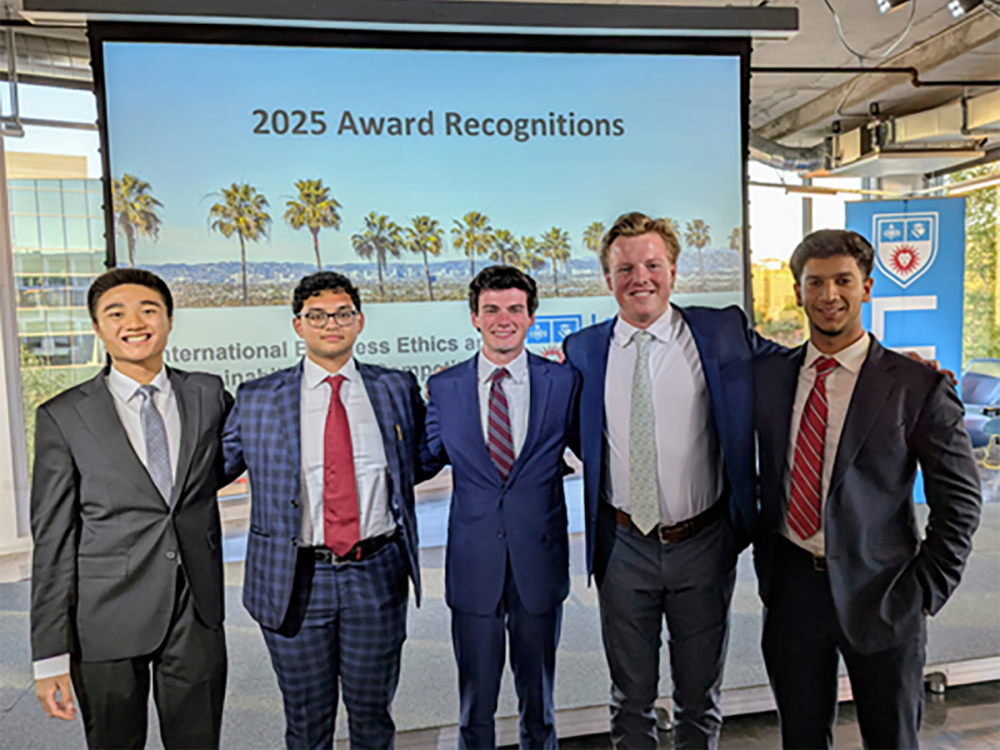 Five men dressed in suits and ties pose in a group.