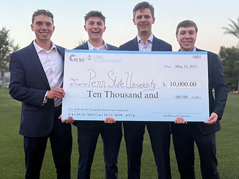 Four young men in suits hold an oversized check for 10 thousand dollars