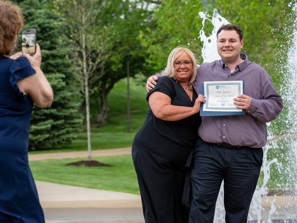 Bryce Landman poses with family by the fountain after receiving the Student of the Year award in Business at Penn State Fayette.