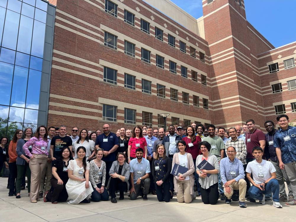 Group of people posing outside of a large brick and glass building
