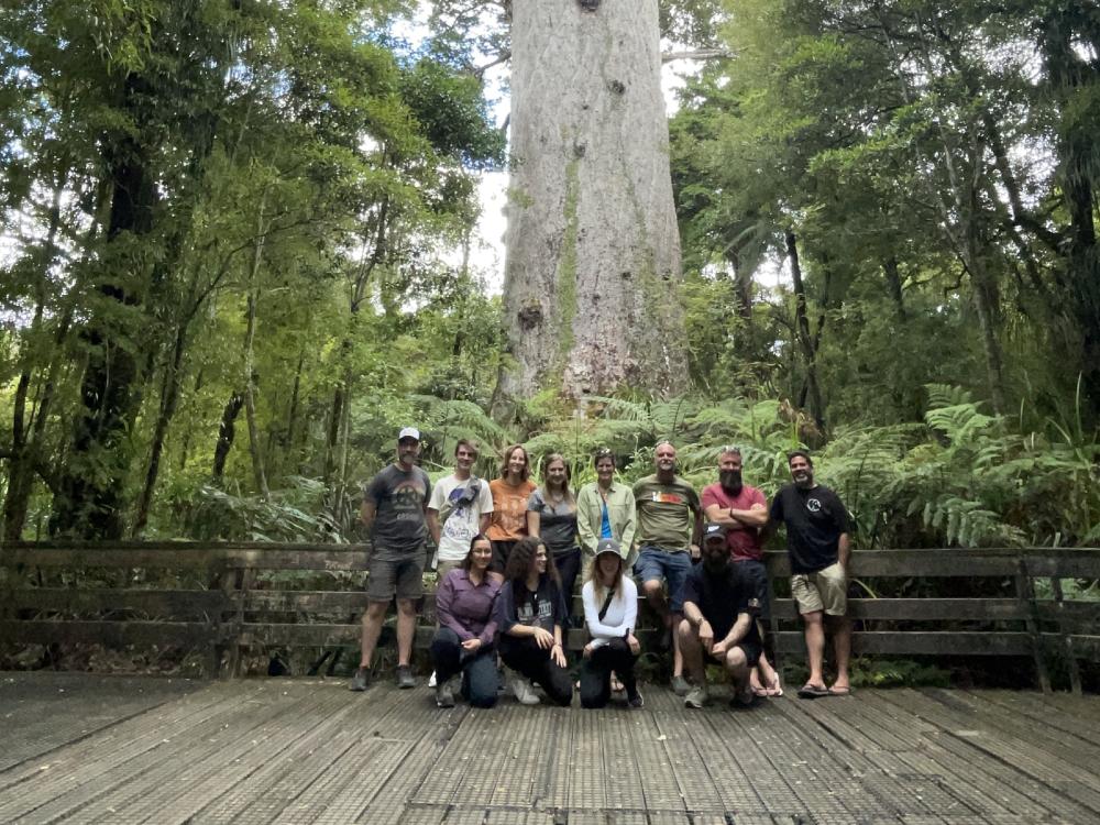 A group of people in front of a large tree