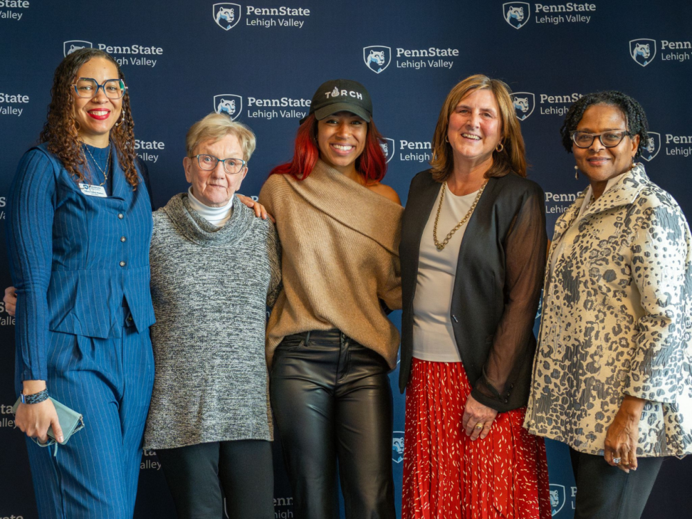 five women smile in front of a Penn State Lehigh Valley banner
