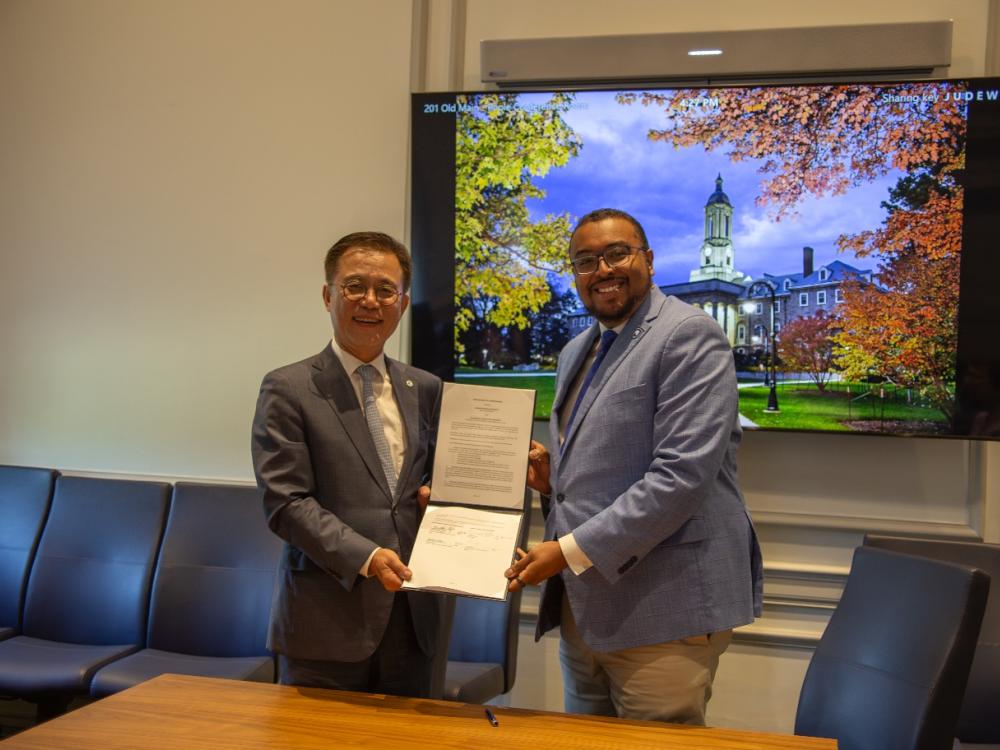 Two men holding a piece of paper and smiling
