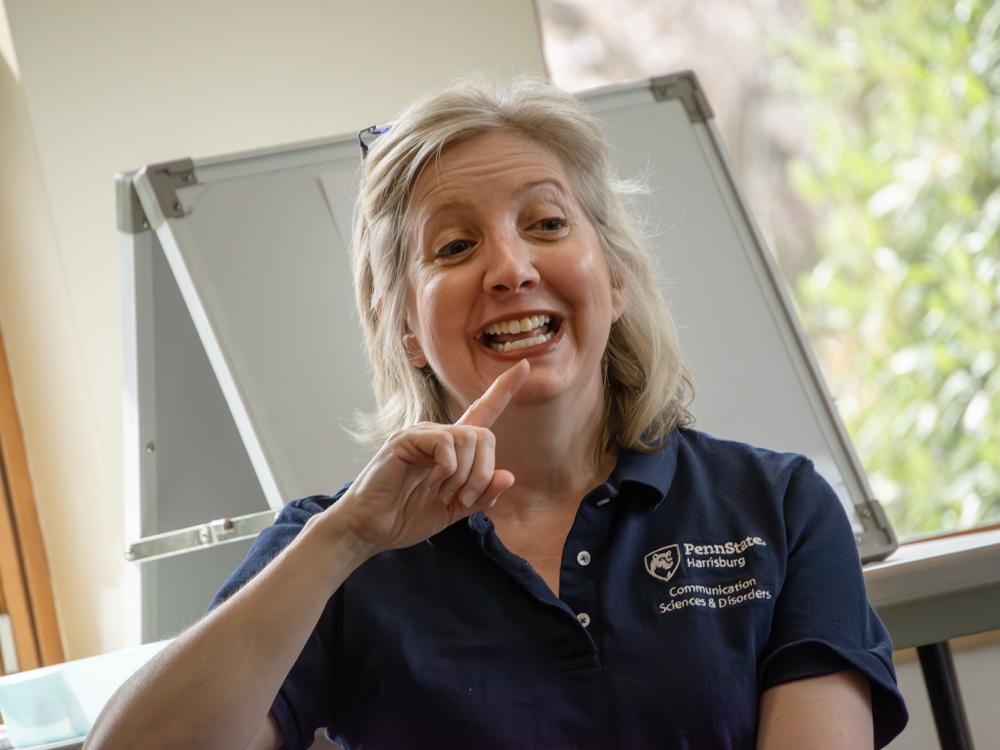 Heidi Haas points to her lips as she demonstrates how to make a sound