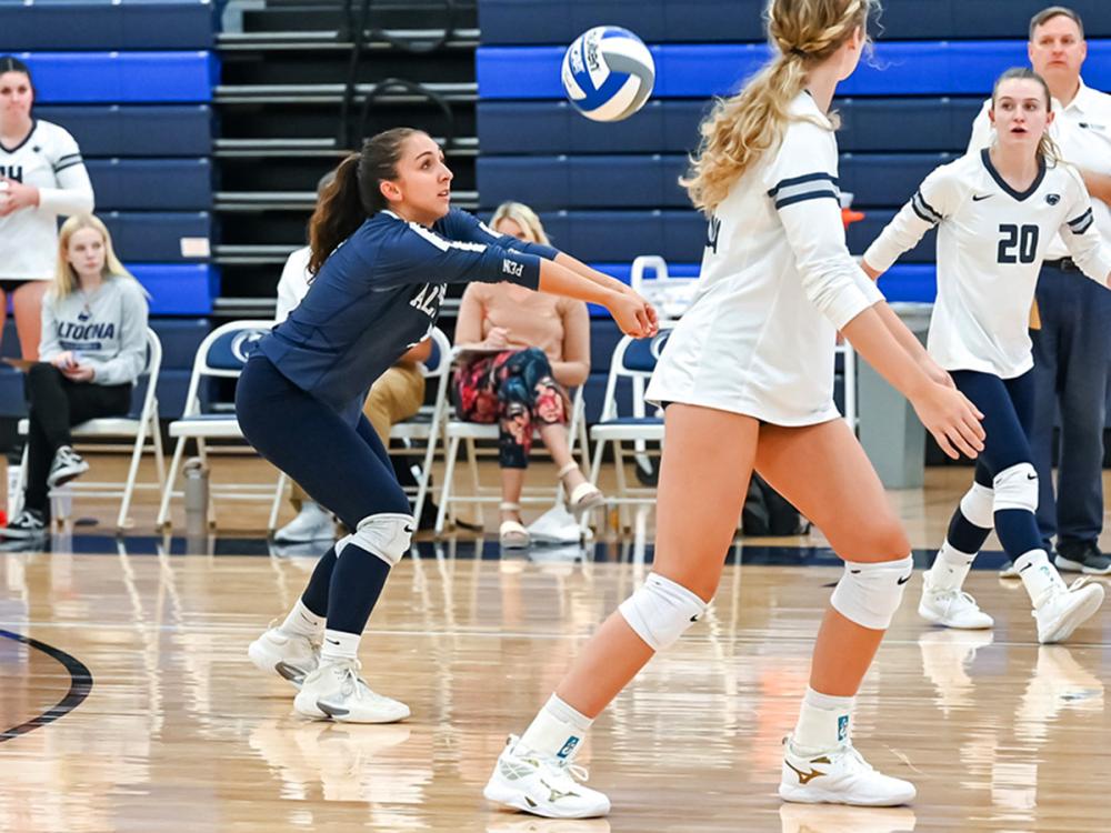 Penn State Altoona volleyball player Anna Batrus prepares to dig during a volleyball game, surrounded by teammates on the court.