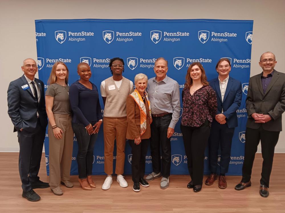 Group of people standing in front of a Penn State Abington banner