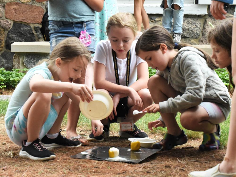 Three girls conduct a science experiment outdoors during Penn State Behrend's College for Kids program.