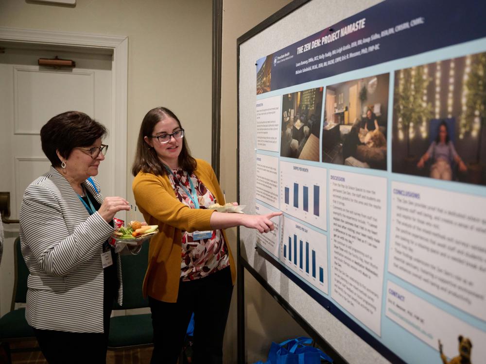 Symposium attendee presenting research at the event's poster presentation.