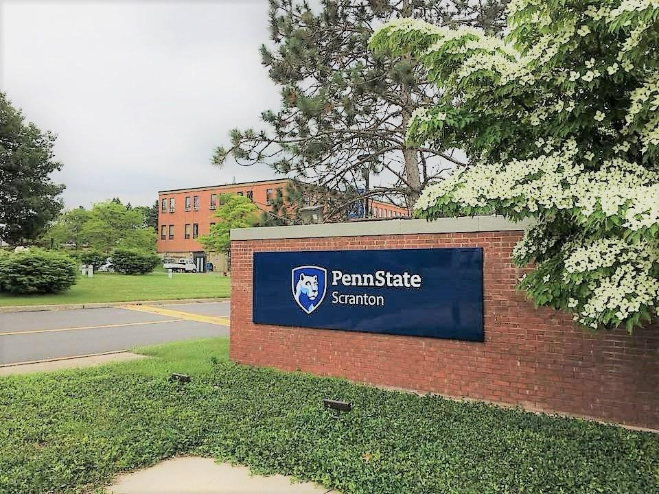 entrance to the campus with the red brick entrance sign reading Penn State Scranton and campus logo