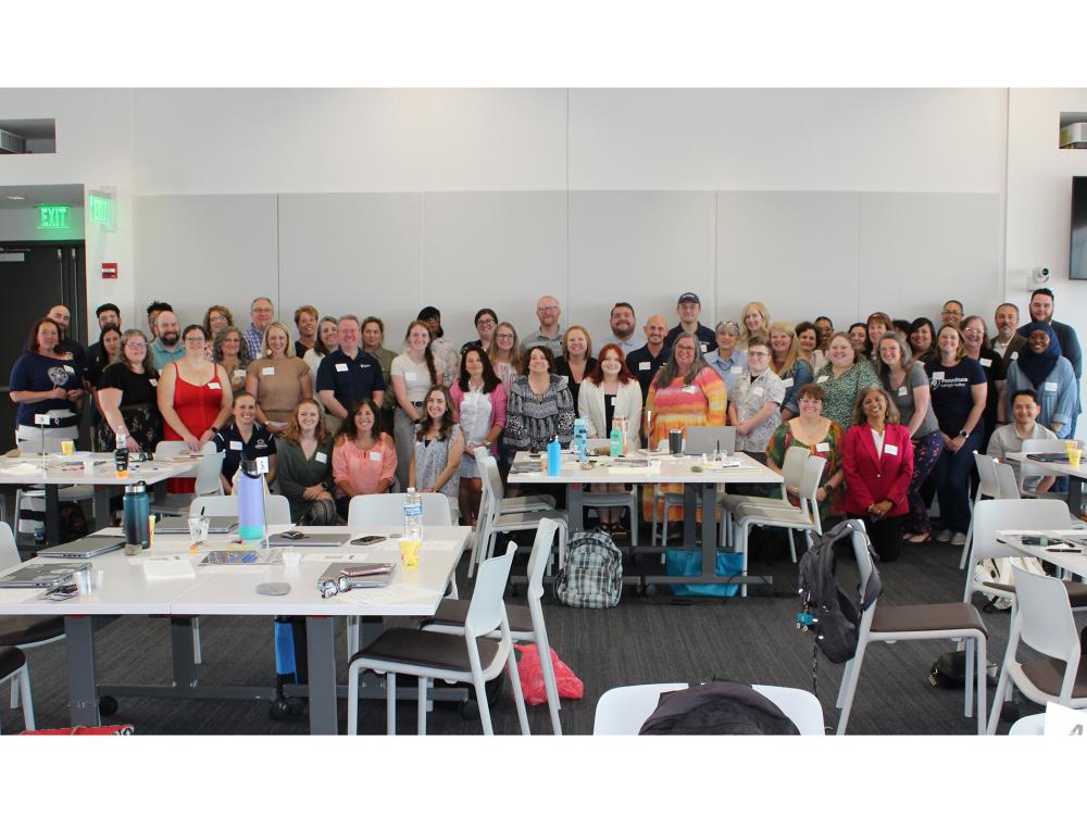 a large group of people pose together for a photo in a conference room