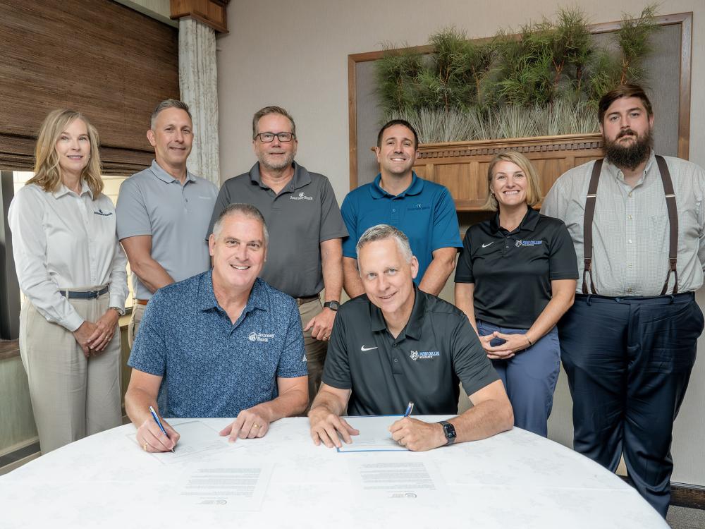 A group of people sit around a table to sign a document