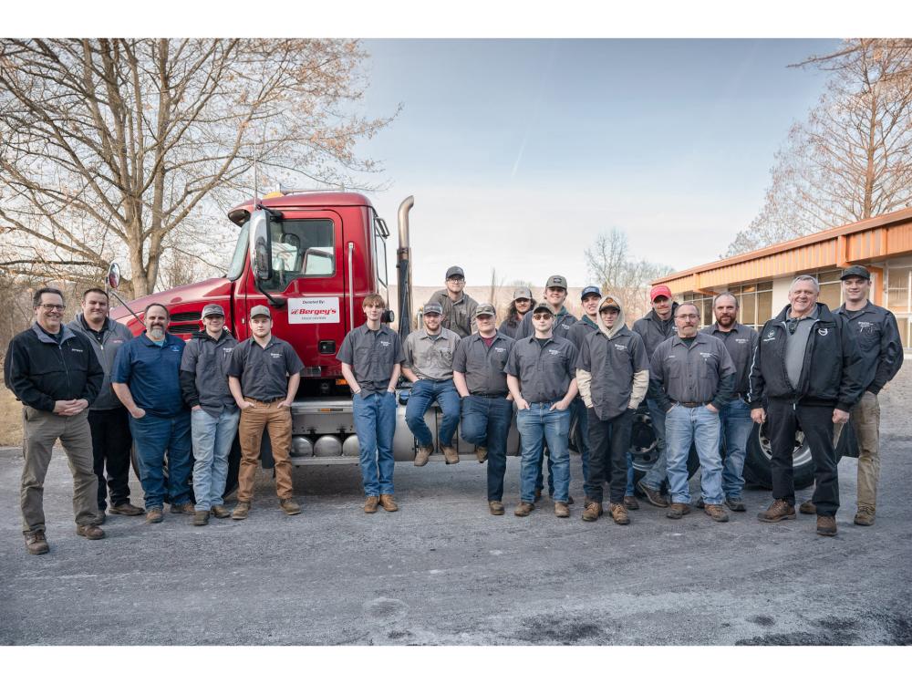 A group of people stand alongside a Mac truck.