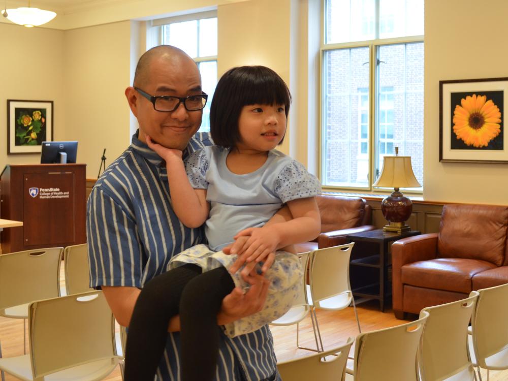 Mark Ramos holds his duaghter Mabel in a room on Penn State University Park campus