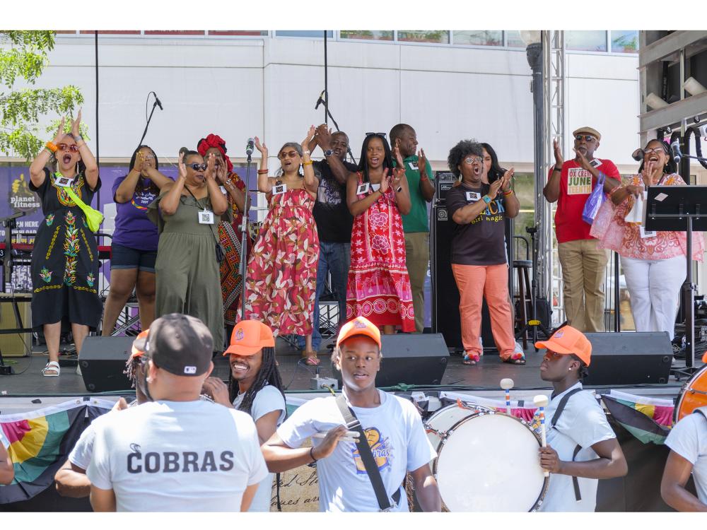 A group of people dancing joyously on a covered stage