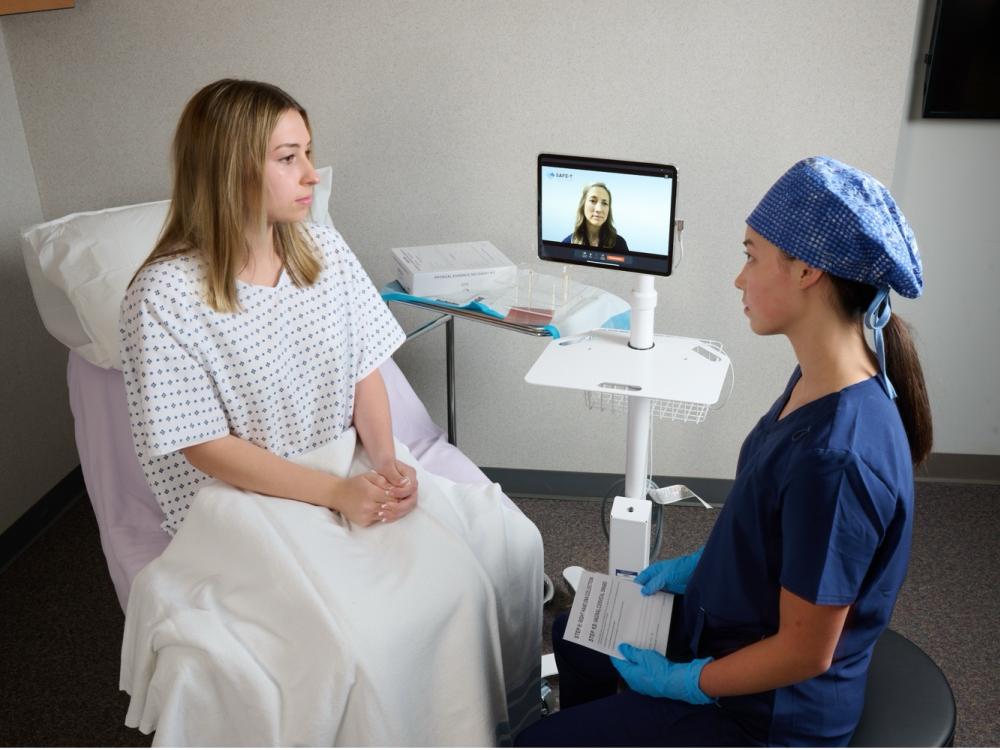 Simulated photo of a nurse using telehealth technology to support trauma-informed care for the patient in a clinical setting.