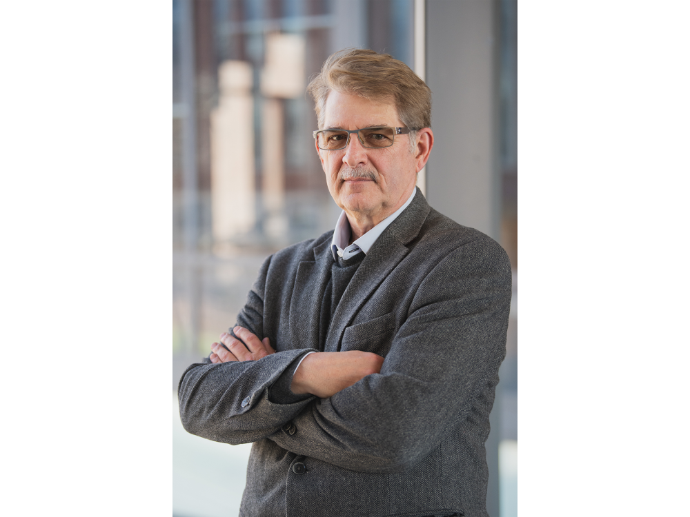 portrait of professor standing with arms crossed across his chest