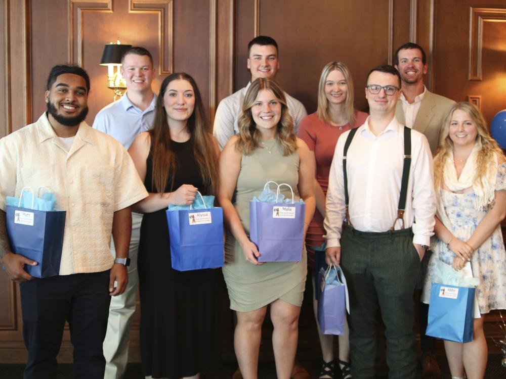 Group of nine students pose with blue gift bags