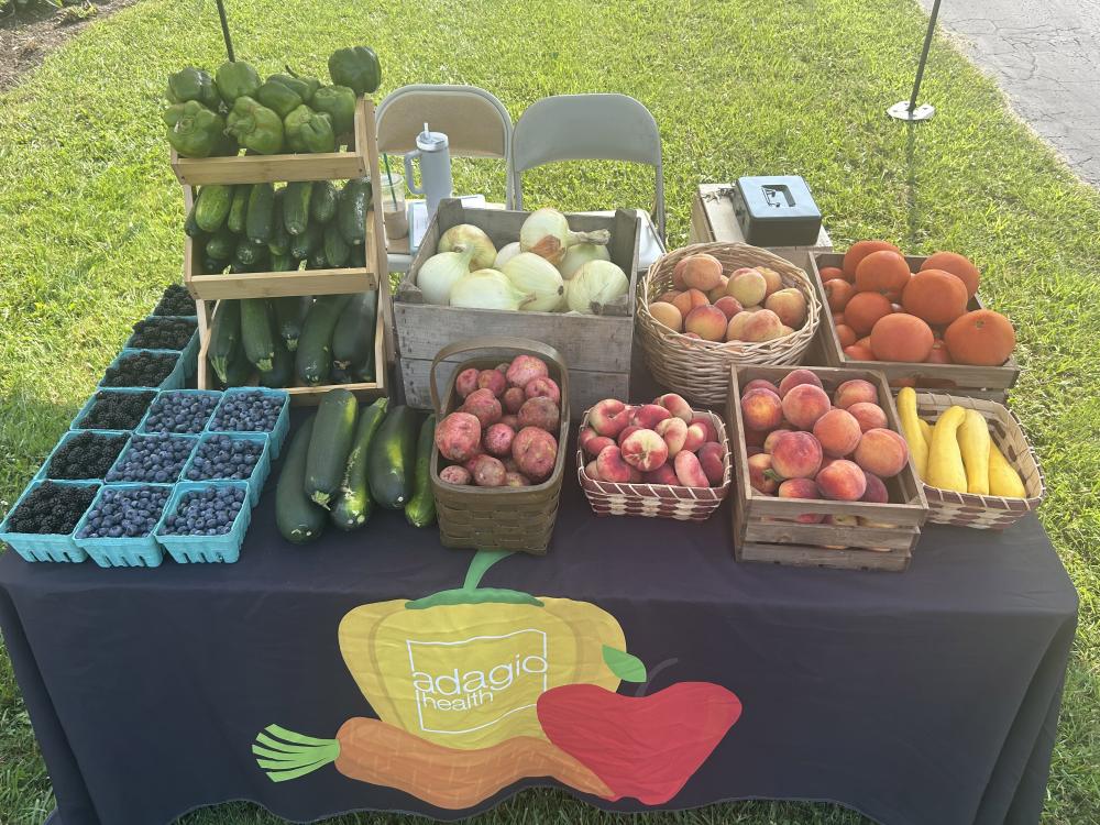 fresh produce in baskets on a table with an "Adagio Health" tablecloth