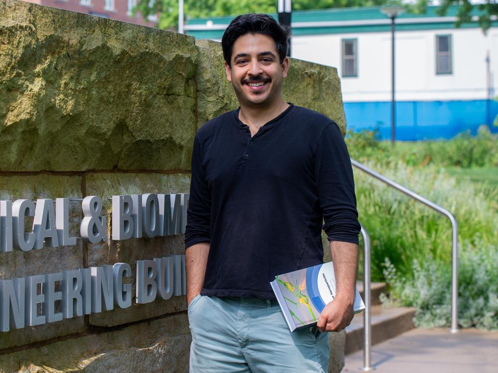 Associate professor poses for headshot next to Chemical and Biomedical Engineering Building sign on Penn State's University Park campus.