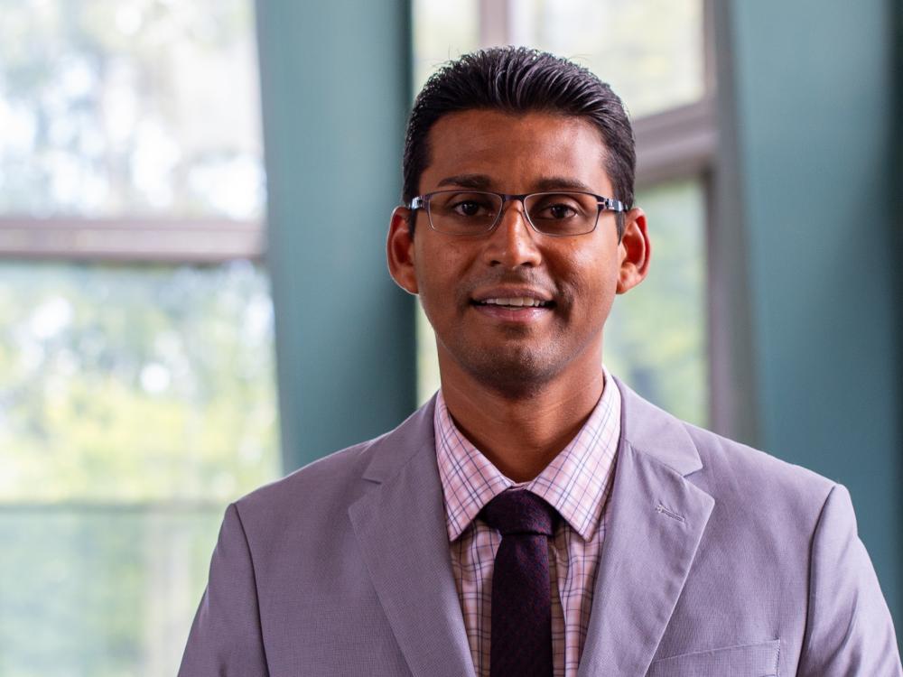 An indoors portrait of an individual wearing a suit and tie.