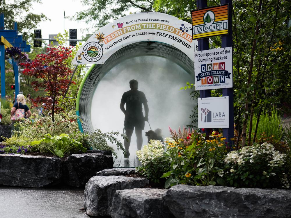 A man walks his dog through a tunnel spraying misty water
