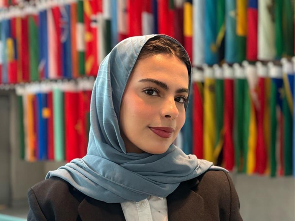 A dark-haired woman wearing a light blue/gray hijab