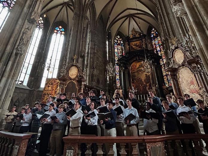 A large group of male college students singing in a cathedral