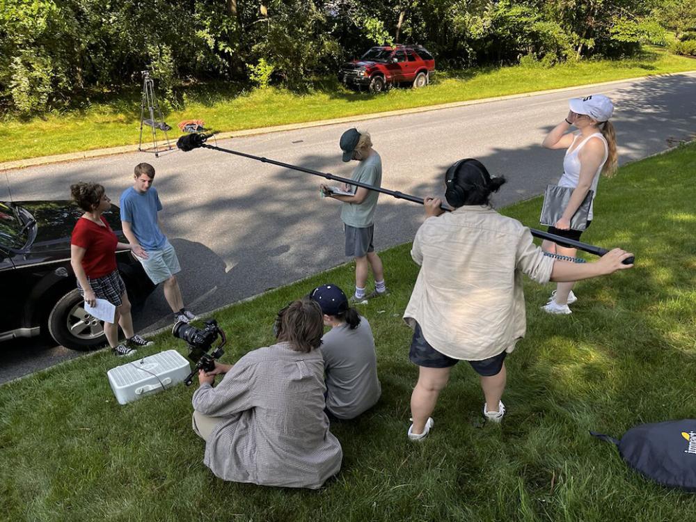 Two actors surround by a film and sound crew