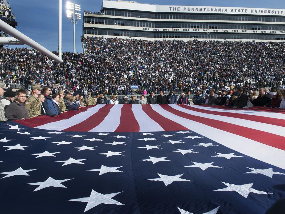 A giant American flag stretches across the end zone at Beaver Stadium.