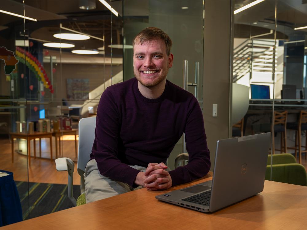 Master of AI student Nicholas Gahman sits at a desk in front of a laptop in Penn State Great Valley's Technology Commons.